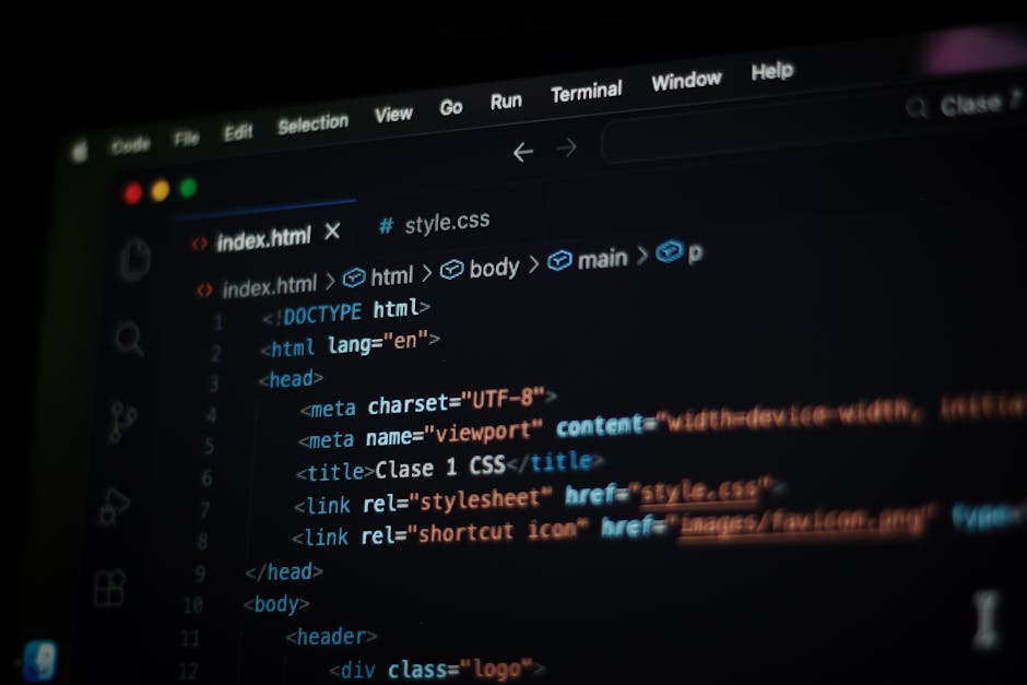 A person working on a laptop computer with a dark-themed code editor visible on the screen, situated on a black table. The individual's hands are positioned over the keyboard, suggesting active typing